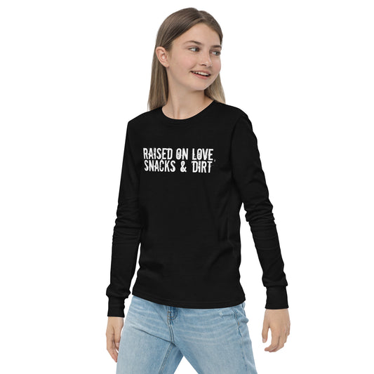 The front view of a black long-sleeve shirt with the words "Raised on love, snacks & dirt" across the chest in a grungy white font