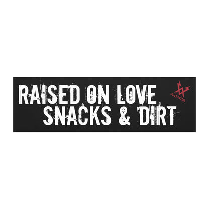 Black car magnet that says "Raised on love, snacks & dirt" in a grungy white font and features a red Voltastra logo in the top right corner.